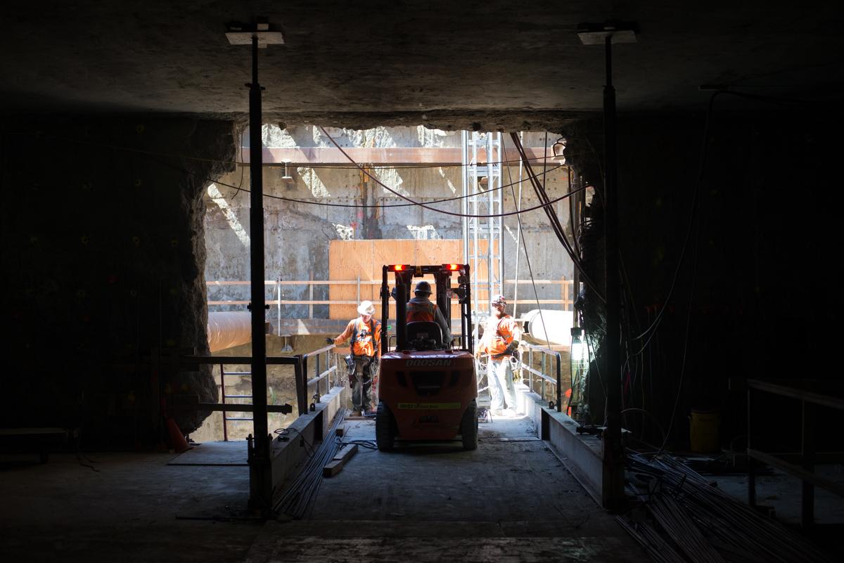Construction workers operate equipment inside tunnel entrance at Yerba Buena-Moscone Station.