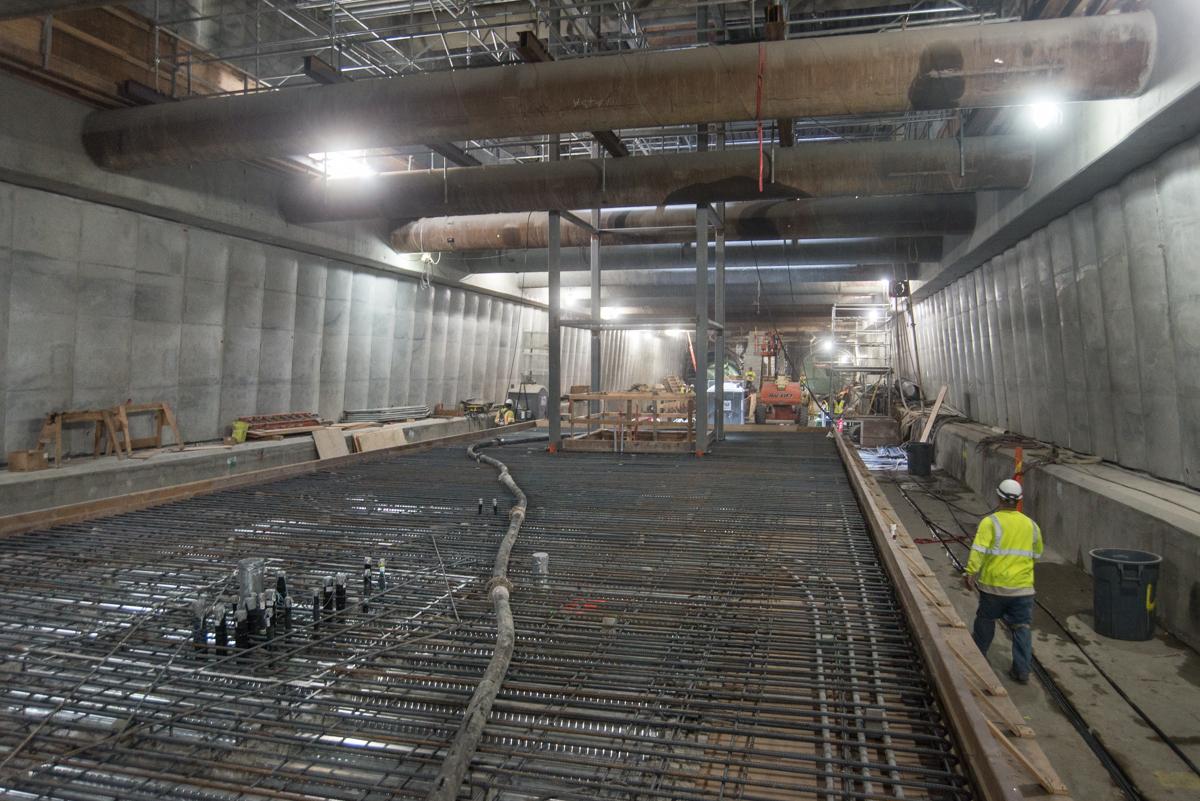 Worker in yellow vest installing rebar for emergency egress staircase construction at transit station.