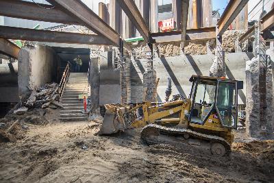 Construction site at Ellis and Stockton with excavator and exposed structural beams from former BART/Muni station entrance.