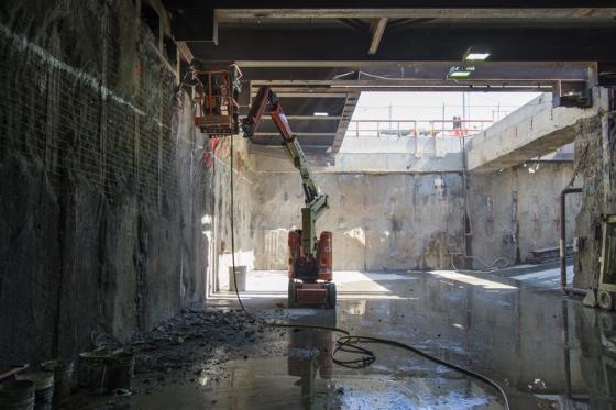 Underground construction site at 4th Street with excavator and water pooling on floor