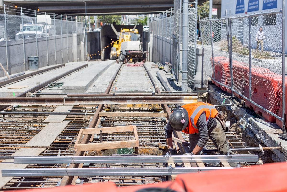 Worker in orange vest assembling rebar cage for surface tracks leading to tunnel portal on 4th Street.