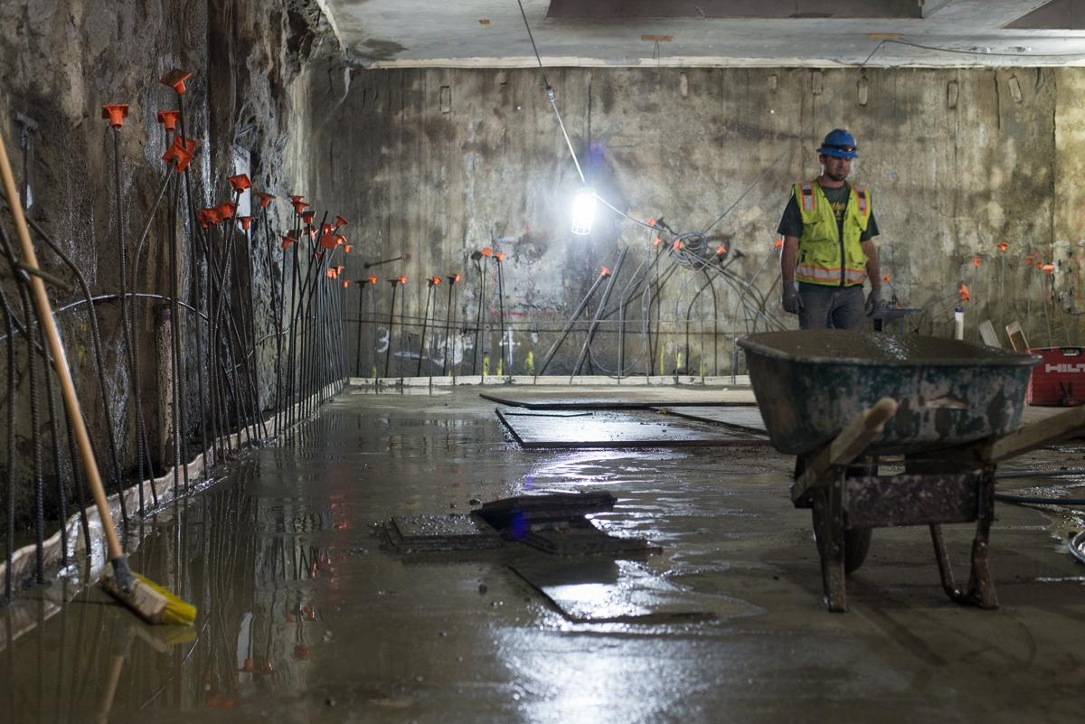 Worker in safety vest stands in flooded underground station during excavation and construction work.