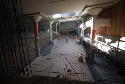 Union Square Garage interior under construction with exposed concrete floor, metal barriers, and construction equipment visible.