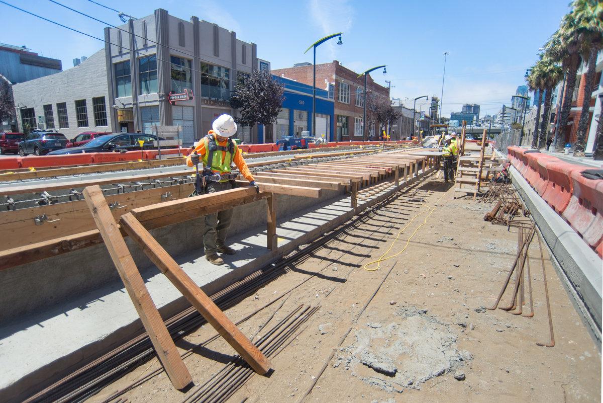 Construction workers install wooden forms and rebar for the 4th and Brannan surface station platform.