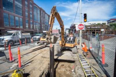 Construction excavation on urban street with heavy equipment and utility work in progress.
