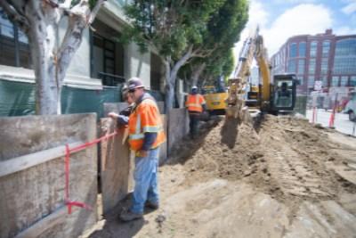 Construction workers and heavy equipment excavating 4th Street for sewer force main installation.