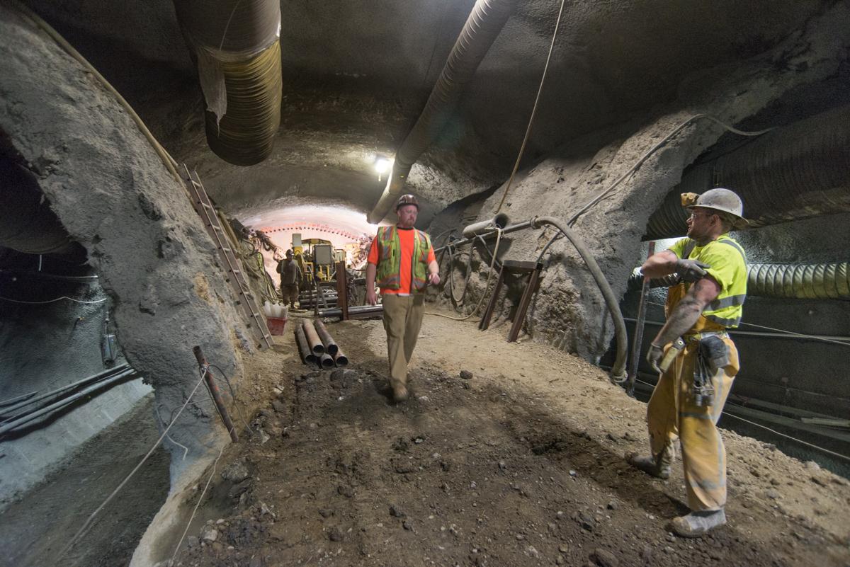 Workers in safety gear inside underground tunnel during Chinatown Station construction excavation work.