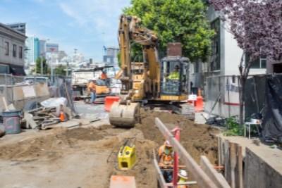 Construction equipment and workers installing utility lines at 4th Street and Townsend Street intersection.