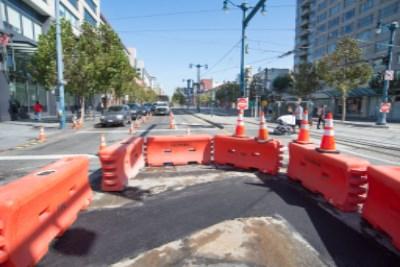 Construction site at 4th and King with red barriers, excavation pit, and utility work in progress on city street.