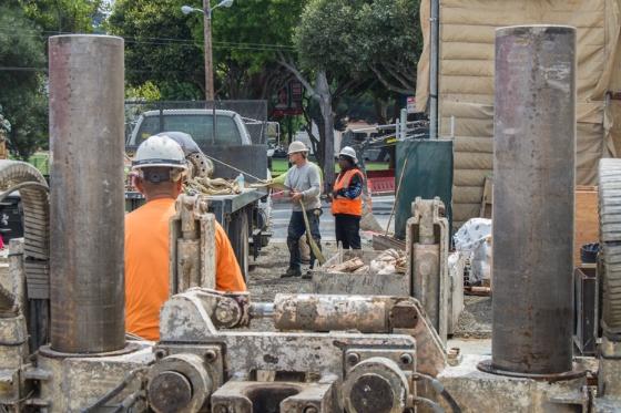 Workers load large metal tunnel boring machine components onto equipment at North Beach retrieval shaft.