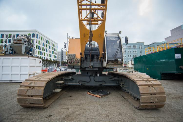 Excavator with bucket positioned over trench for underground station construction on 4th Street.