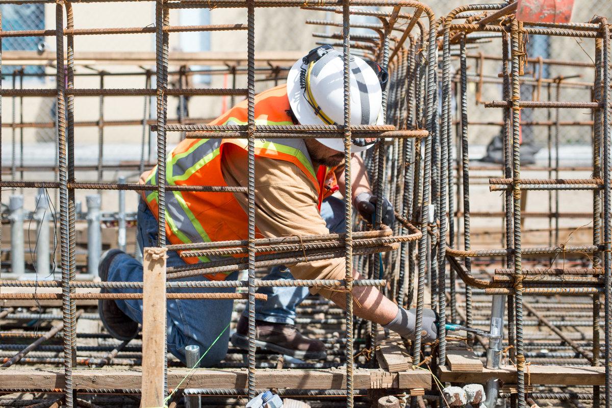 Construction worker in safety gear assembling rebar cage at 4th and Brannan station platform.