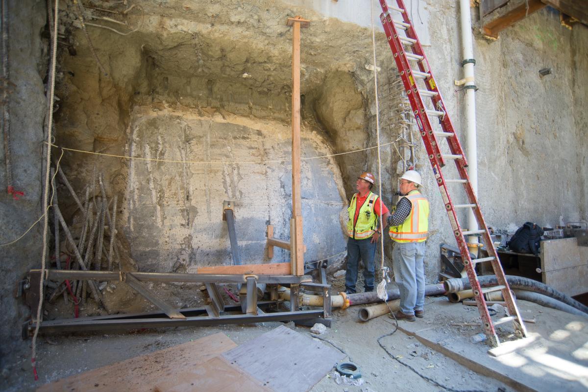 Two workers in safety vests inspect underground tunnel construction at Yerba Buena-Moscone Station.