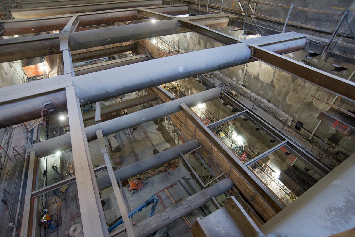 Underground station excavation showing steel bracing, struts, and cross-beams supporting structural framework during construction.