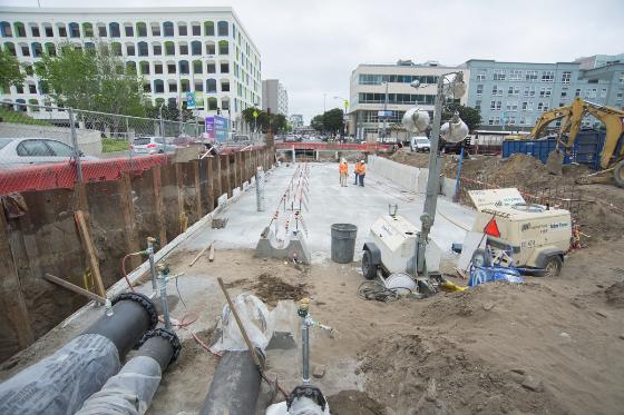 Construction site with concrete foundation, pipes, and equipment for future Yerba Buena/Moscone Station on 4th Street.