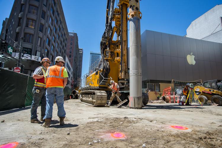 Construction workers and equipment at Ellis and Stockton streets marking locations for underground wall sections.