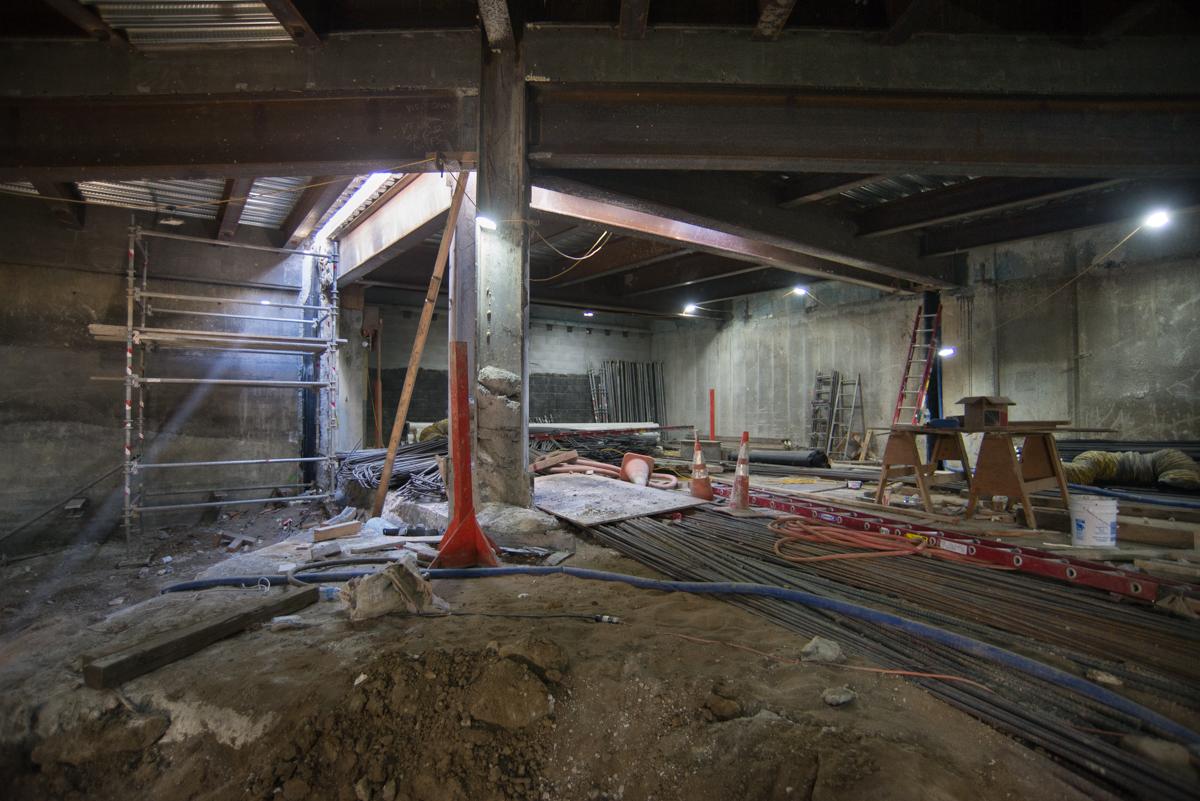 Construction site showing temporary bracing, excavation equipment, and exposed concrete walls under underground station structure.