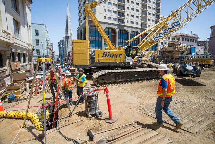 Construction workers and heavy equipment at Chinatown Station site on Stockton Street.