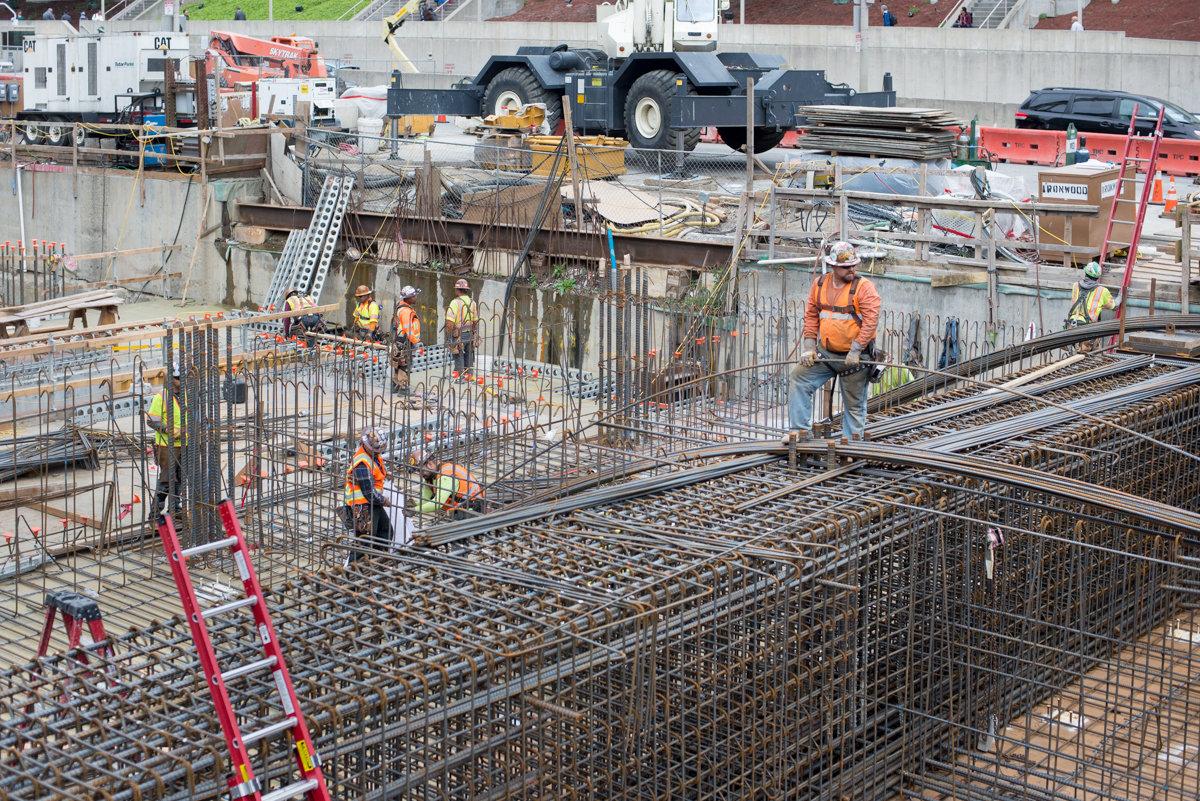 Construction workers install reinforced steel rebar framework at downtown transit project site.