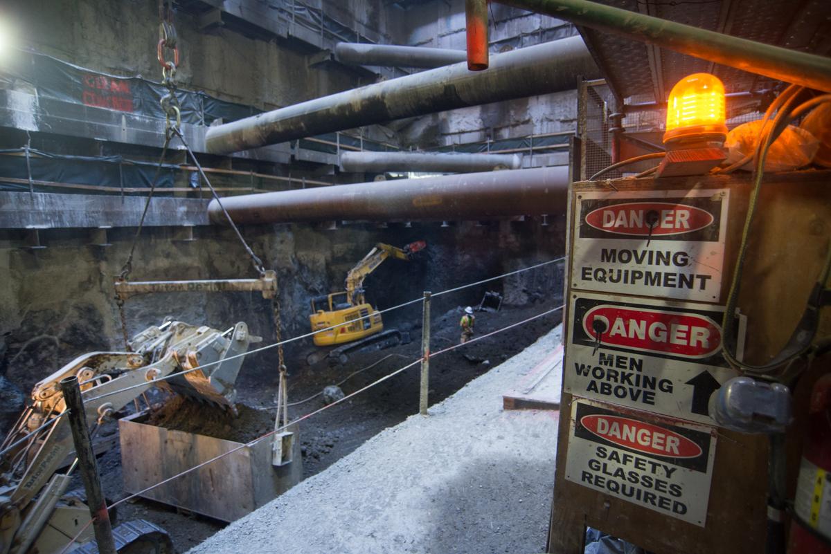 Excavator with jackhammer removing concrete from headhouse slurry walls at Chinatown station construction site.