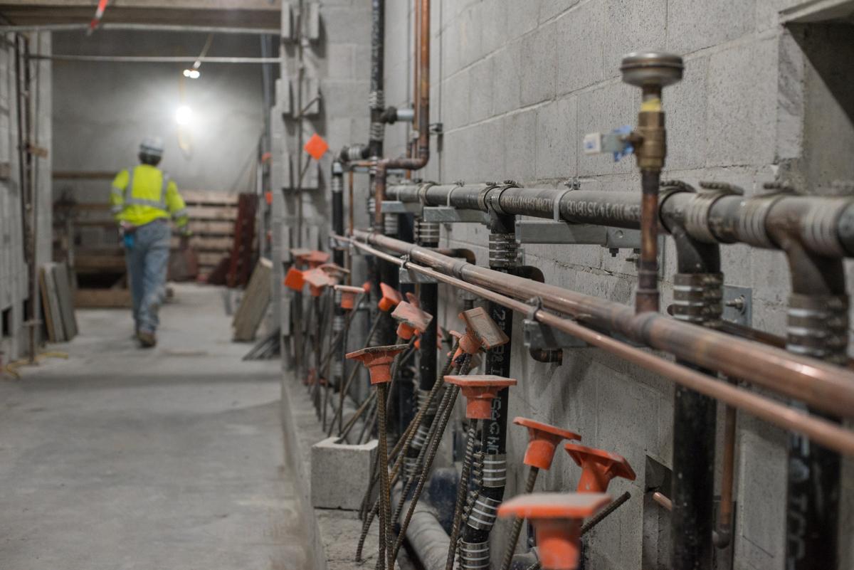 Newly-installed plumbing pipes and valves mounted on an interior concrete wall in an underground transit station.