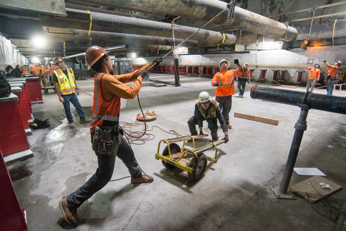 Construction workers lower rebar into Union Square/Market Street station box for Central Subway project.