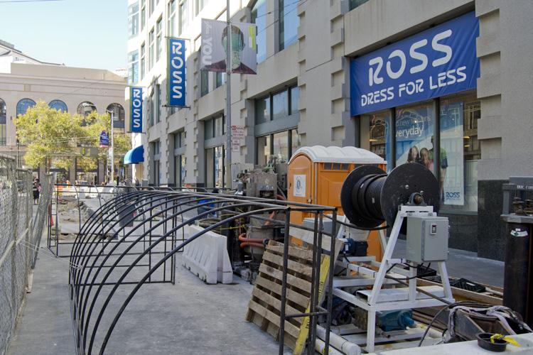 Construction equipment and metal framework on 4th Street sidewalk with Ross store and downtown buildings visible.
