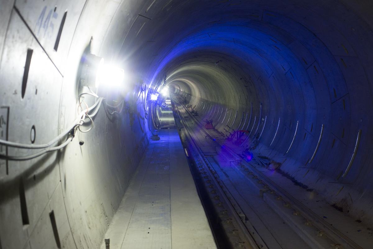 Southbound tunnel with blue lighting at cross-passage 5, railroad tracks visible ahead.