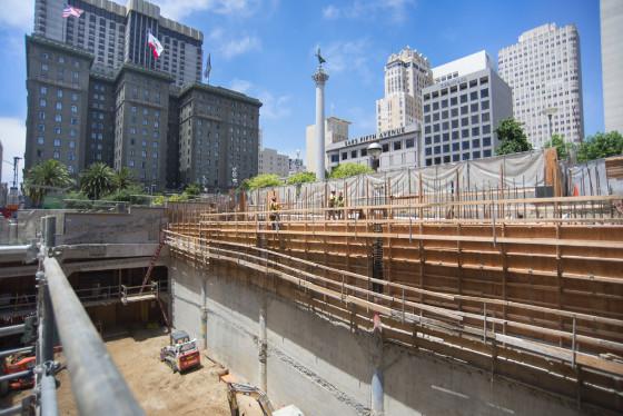 Construction site at Union Square Garage with concrete forms, rebar, and downtown San Francisco skyline visible.