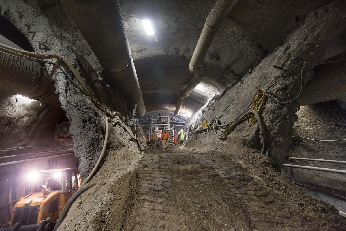 Underground tunnel excavation with heavy equipment and workers at Chinatown Station construction site.