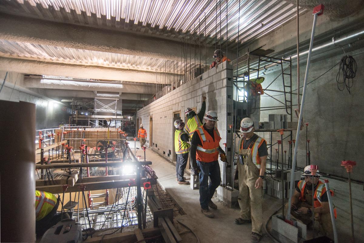 Construction workers in safety vests build rebar-reinforced interior walls on a mezzanine level at Union Square/Market station.
