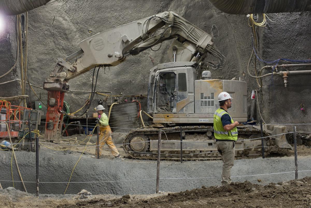 Excavator and workers at underground construction site for Chinatown Station platform cavern.