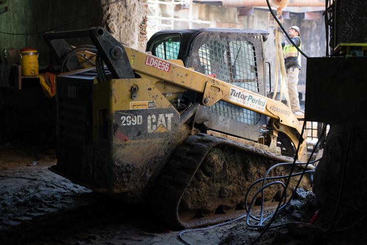 Yellow Caterpillar bobcat skid-steer loader excavating dirt at a construction site on Folsom Street.