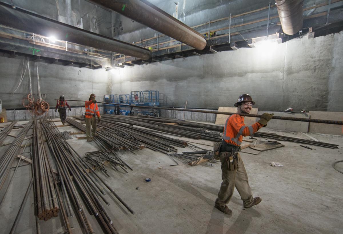 Workers handle steel rebar in underground construction area at Union Square station.