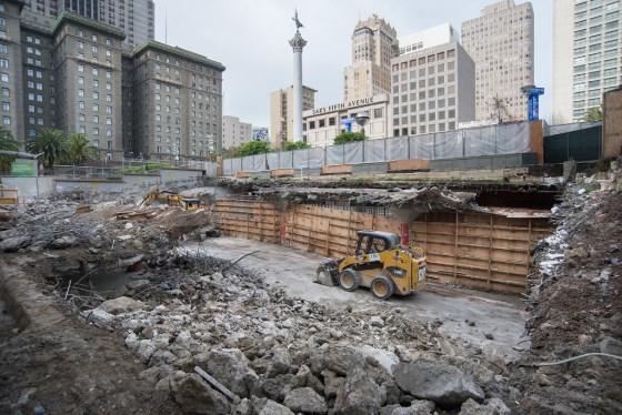 Construction site with heavy equipment and debris at Union Square Garage demolition area, downtown cityscape visible.