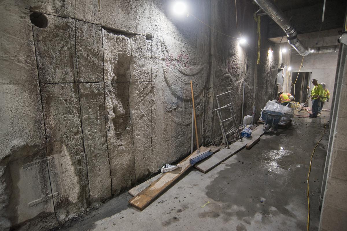 Workers in safety vests construct concrete forms in an underground transit station corridor at night.
