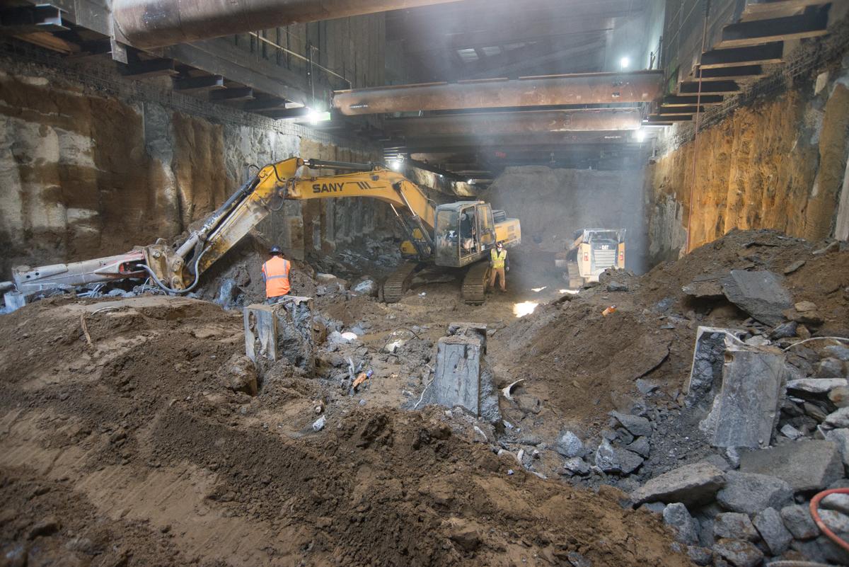 Excavation work underway in underground transit tunnel with yellow SANY excavator and construction equipment.