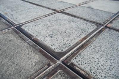 Close-up of newly installed metal track crossing with concrete base slab at street level.