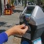Hand inserting card into parking meter on street