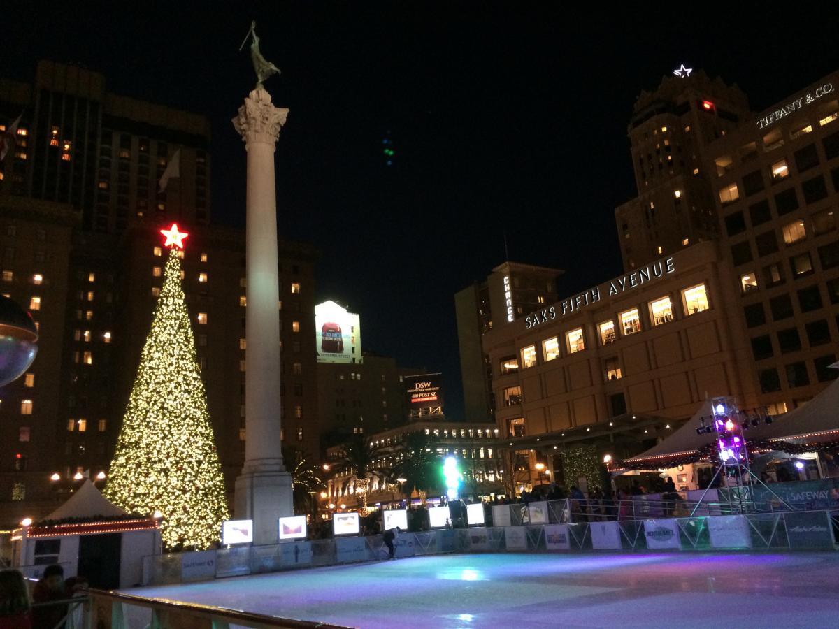 Union Square holiday ice rink at night with illuminated Christmas tree and surrounding buildings.