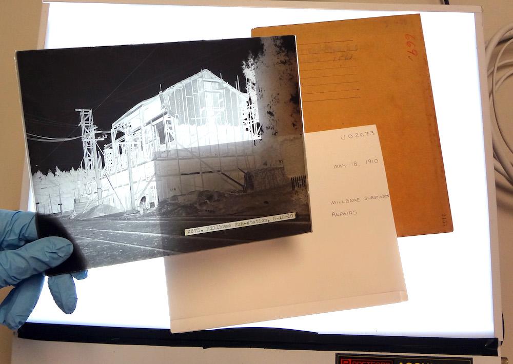 hand holding negative above light table with envelopes in background
