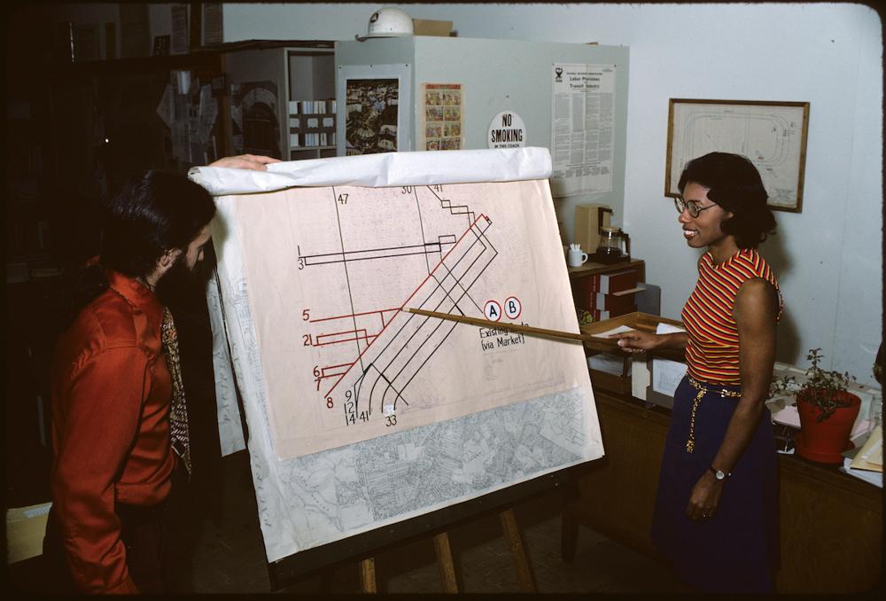 two people standing in front of and pointing at map