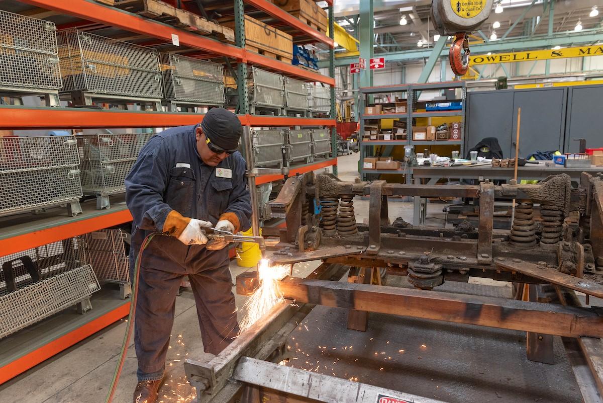 Photo of a worker welding a metal cable car frame