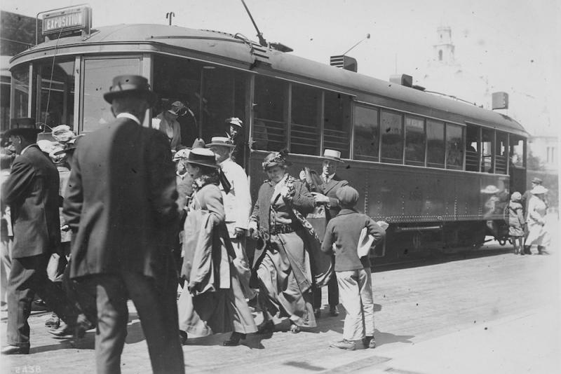 group of people walking away from streetcar. car is headsigned "Exposition".