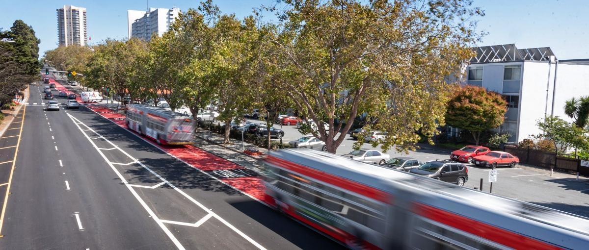 Image of two Geary buses traveling through Japantown in red bus lanes.