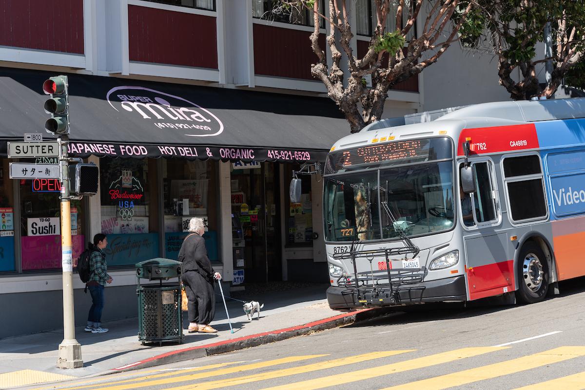 Coach approaching a stop on a downhill grade at an intersection with passengers about to board