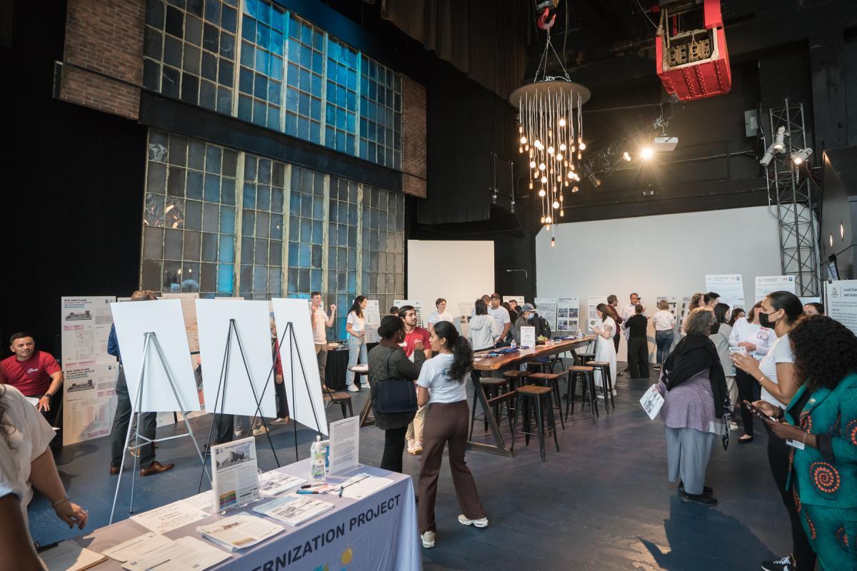 Full view from the welcome table of Z Space in Potrero Yard with staff and community members standing by Project Boards