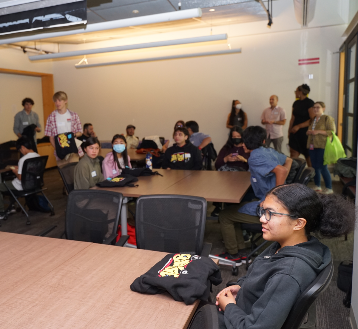 Crowd of youth in a conference room in conversation.