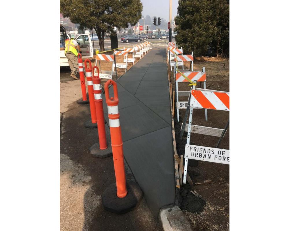 Concrete path, still wet, with construction barriers surrounding