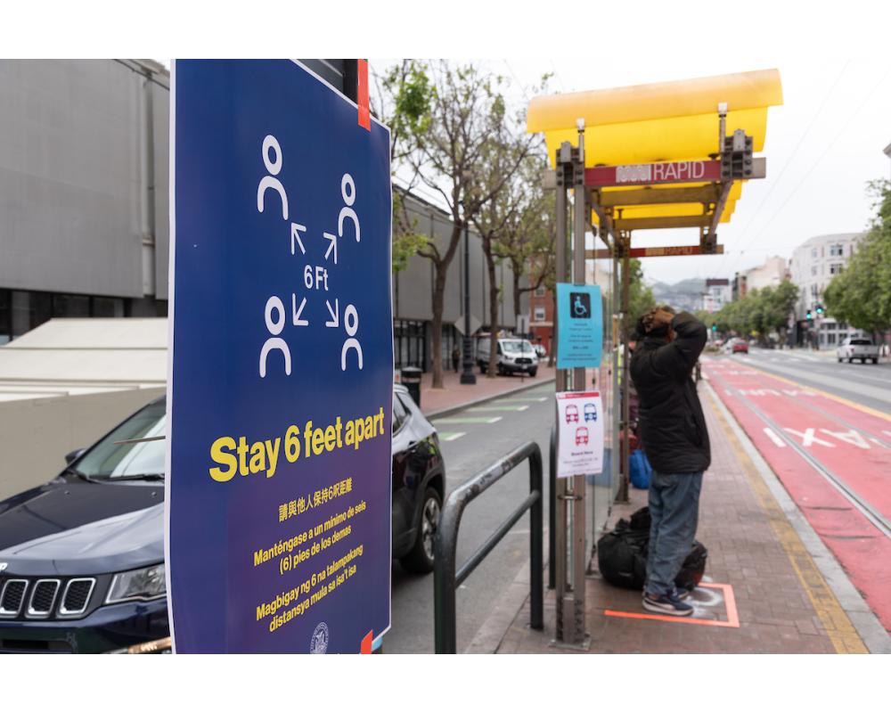 Signage and ground markings at Muni stops encourage physical distancing.